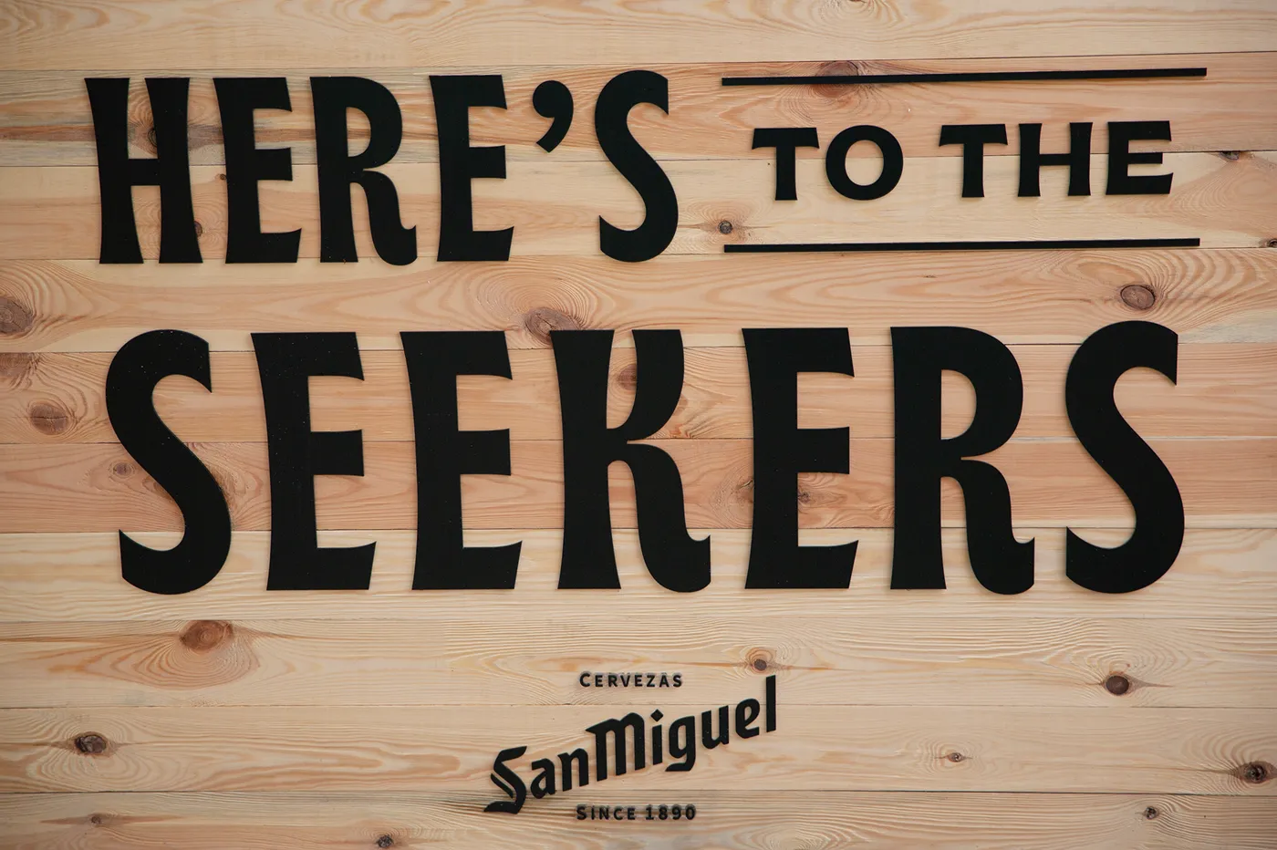 Wooden panel with San Miguel logo and the phrase “Here’s to the Seekers”.